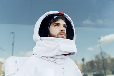 Thoughtful male astronaut in space suit looking away in city