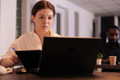 Businesswoman using laptop while sitting on table