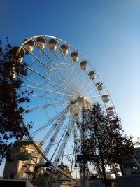 Low angle view of ferris wheel against clear blue sky