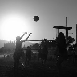 Silhouette people playing basketball against sky