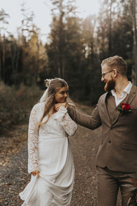 Young couple standing on land against trees