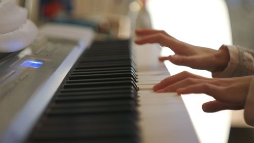 Cropped hands of woman playing piano