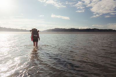 Rear view of woman standing in water against sky