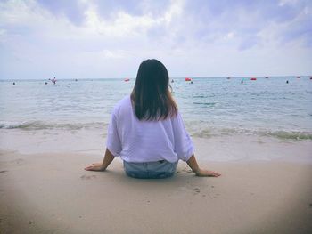 Rear view of woman sitting at beach