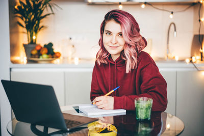 Portrait of young woman using laptop at table