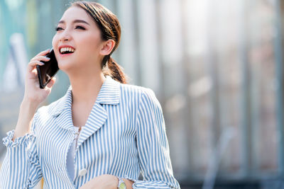 Young woman looking away while standing on mobile phone