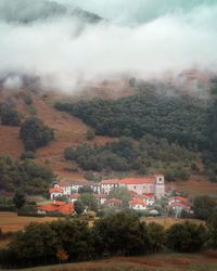 Houses by trees and buildings against sky