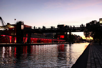Illuminated city by river against clear sky