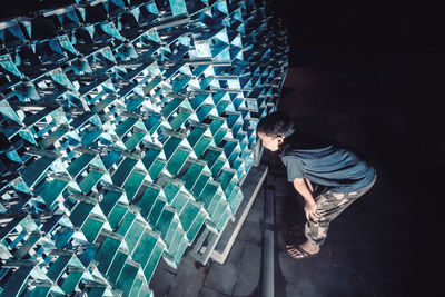 Boy looking at metallic structure during night