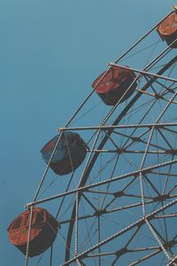 Low angle view of ferris wheel in the city against clear blue sky