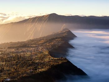 Scenic view of sea against mountains during sunset