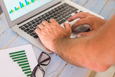 Midsection of man using laptop on table