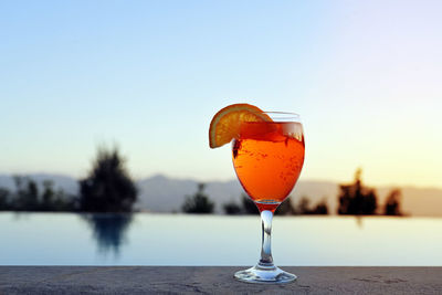 Close-up of wineglass on table against sky during sunset