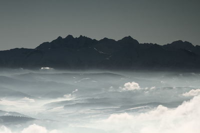 Scenic view of cloud covered mountains against clear sky