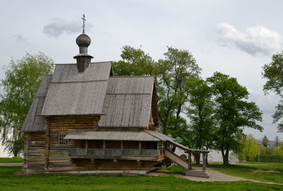 Built structure by trees on field against sky