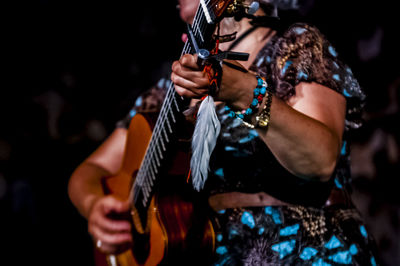 Midsection of female musician playing guitar during concert