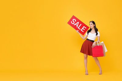 Woman with umbrella against yellow background