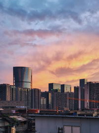 Modern buildings against sky during sunset