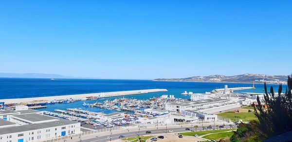 High angle view of sea by buildings against blue sky