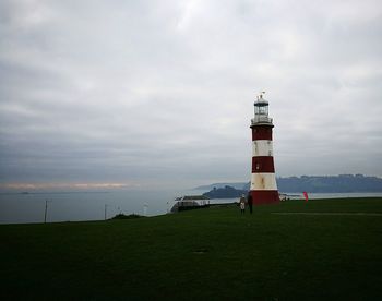 Lighthouse by sea against sky