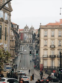 Traffic on road amidst buildings in city against sky