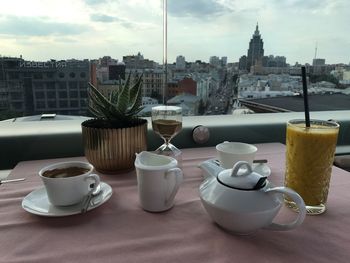 Coffee cup on table against sky in city