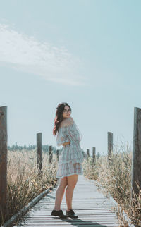 Woman standing on field against sky