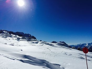 Snow covered landscape against blue sky