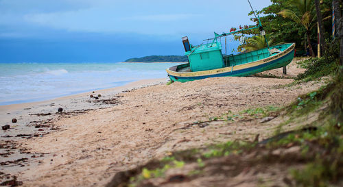 Boat moored on beach against sky