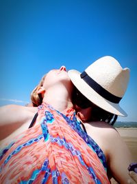 Low section of woman wearing hat against clear blue sky