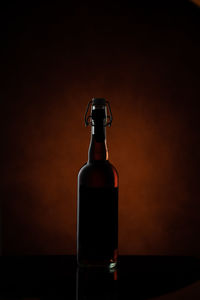 Close-up of glass bottle on table against black background