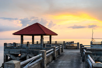 Lifeguard hut on sea shore against sky during sunset