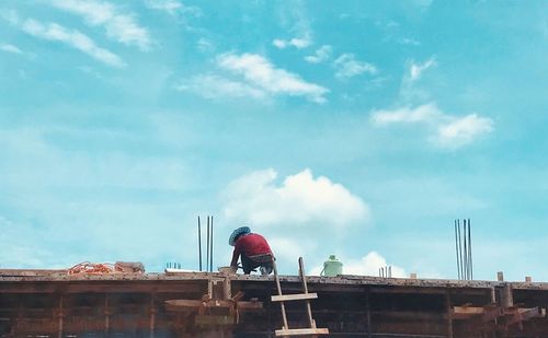 Low angle view of man working at construction site against sky