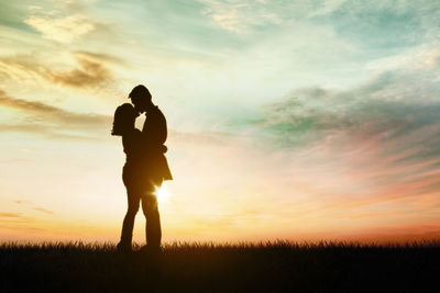 Silhouette man standing on field against sky during sunset