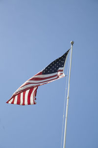 Low angle view of flags against clear blue sky