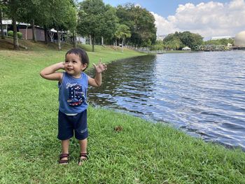 Boy standing on grass by water