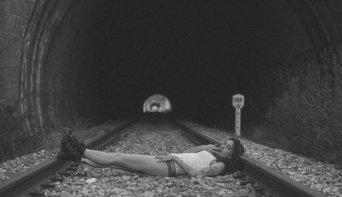 Portrait of woman lying down on railroad track