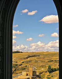Built structure on landscape against cloudy sky