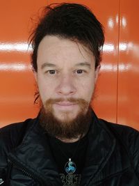 Portrait of young man against orange wall