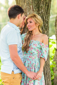 Young couple standing against tree