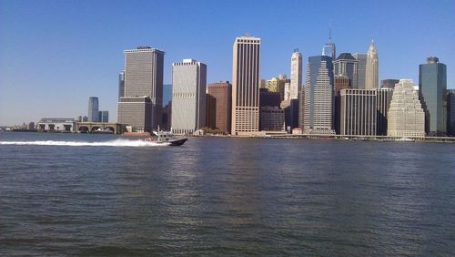 Modern buildings in front of river on sunny day in city