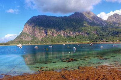 Scenic view of boats on lake in front of mountains against cloudy sky