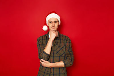 Portrait of man standing against red background