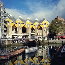 Boats moored in city against cloudy sky