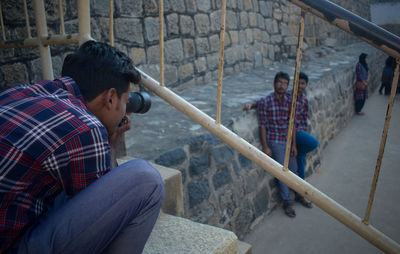 Man photographing friends standing on footpath