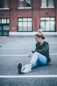 Full length of woman sitting in front of building