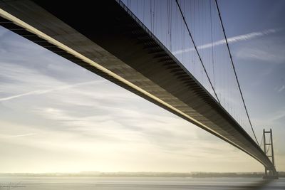 Low angle view of humber bridge over river at sunset