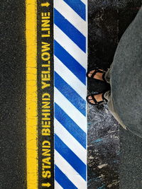 Low section of man standing by road sign on street 