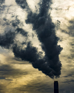 Low angle view of smoke emitting from chimney against sky