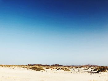 Scenic view of desert against clear blue sky